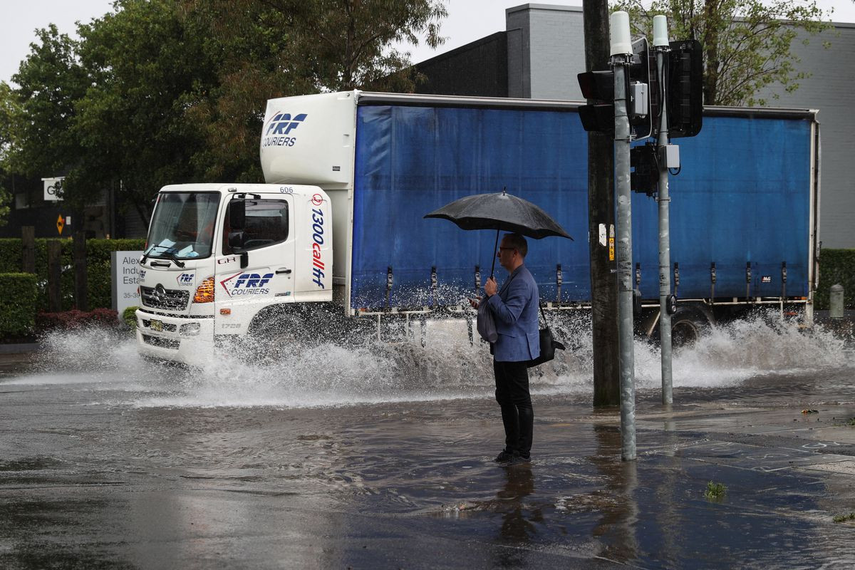 a pedestrian stands on the corner of a flooded street as heavy rains affect sydney australia october 6 2022 reuters loren elliott