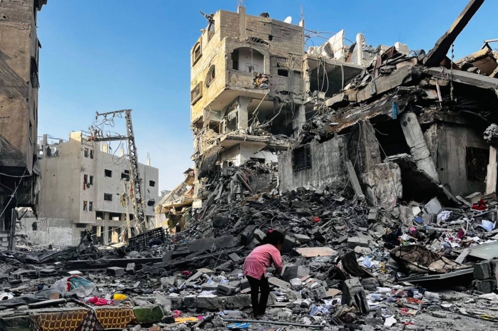 a palestinian girl looks through the rubble of a building after an israeli strike in beit lahia in the northern gaza strip on october 29 2024 photo afp