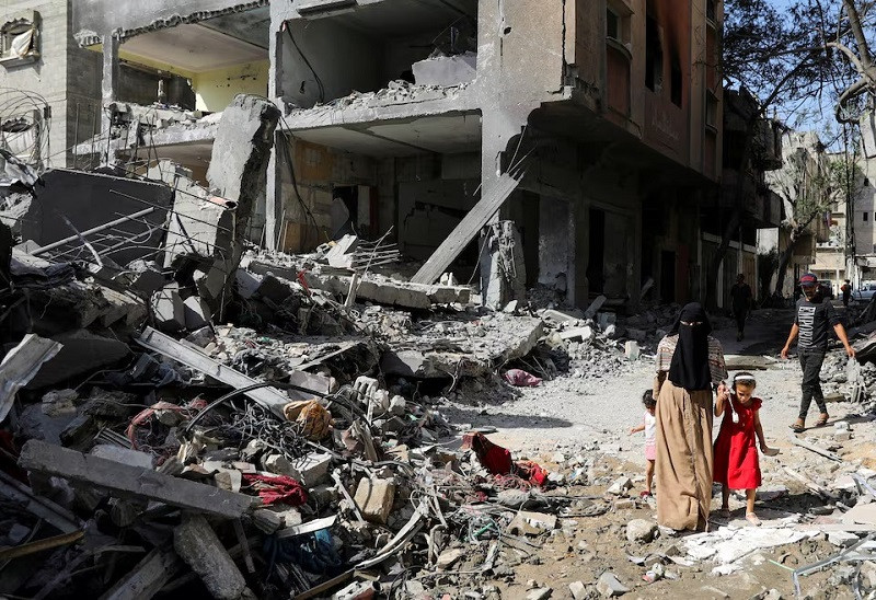 A woman and child walk among debris, in Nuseirat refugee camp in the central Gaza Strip, June 9, 2024. PHOTO: REUTERS