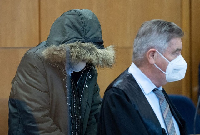 syrian doctor 36 known as m by german media sits with his head covered accompanied by one of his lawyers ulrich endres as he goes on trial in frankfurt germany january 19 2022 he is accused of crimes against humanity with prosecutors saying he physically and mentally tortured political prisoners opposed to president assad at an army hospital in homs in 2011 and 2012 before he arrived in germany in 2015 where he continued to practice medicine until his arrest in june 2020 photo reuters