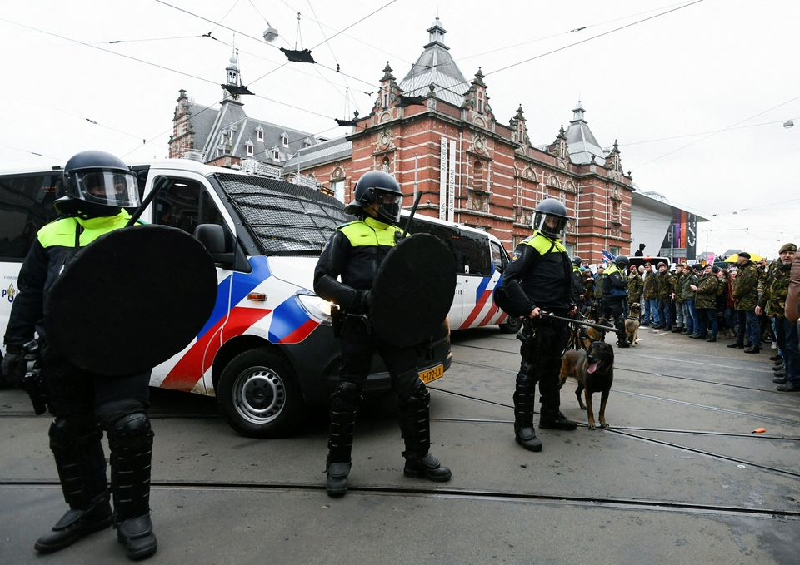 Police officers stand guard as opponents of restrictions imposed in the Netherlands to contain the spread of the coronavirus disease protest despite a ban in Amsterdam. PHOTO: REUTERS