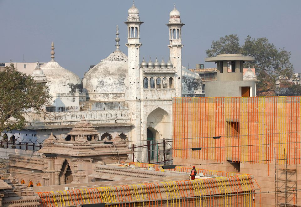 a worker stands on a temple rooftop adjacent to the gyanvapi mosque ahead of the inauguration of the new kashi vishwanath temple corridor by india s prime minister narendra modi in the northern city of varanasi india december 12 2021 reuters