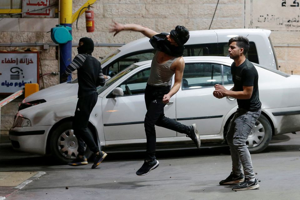 A Palestinian demonstrator hurls stones towards Israeli forces during an anti-Israel protest amid a flare-up of Israeli-Palestinian violence, in Hebron in the Israeli-occupied West Bank May 11, 2021. PHOTO: REUTERS