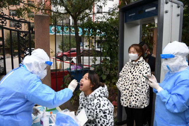 a medical worker in protective suit collects a swab from a resident at a free nucleic acid testing site following new cases of the coronavirus disease covid 19 in lanzhou s chengguan district gansu province china october 20 2021 photo reuters a medical worker in protective suit collects a swab from a resident at a free nucleic acid testing site following new cases of the coronavirus disease covid 19 in lanzhou s chengguan district gansu province china october 20 2021 photo reuters