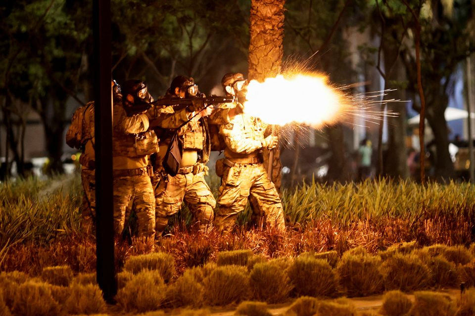 a police officer fires a shotgun as supporters of brazil s president jair bolsonaro protest after supreme court justice alexandre de moraes ordered a temporary arrest warrant of indigenous leader jose acacio serere xavante for alleged anti democratic acts in brasilia brazil december 12 2022 reuters