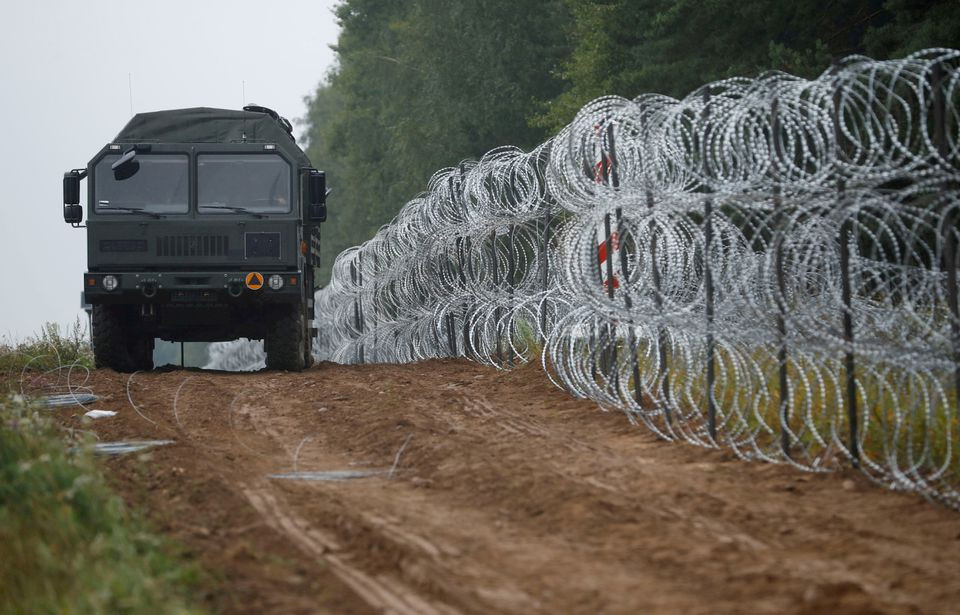 a view of a vehicle next to a fence built by polish soldiers on the border between poland and belarus near the village of nomiki poland august 26 2021 photo reuters