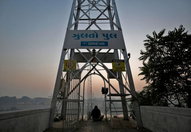 a man sits at the site of a damaged suspension bridge after it collapsed on sunday in morbi town in the western state of gujarat india november 1 2022 reuters