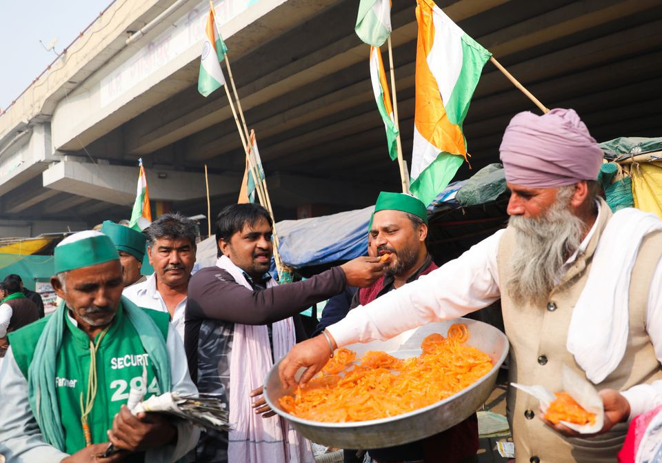 farmers feed each other sweets and celebrate as they pose for pictures after indian prime minister narendra modi announced that he will repeal the controversial farm laws at the ghazipur farmers protest site near delhi up border india november 19 2021 reuters anushree fadnavis