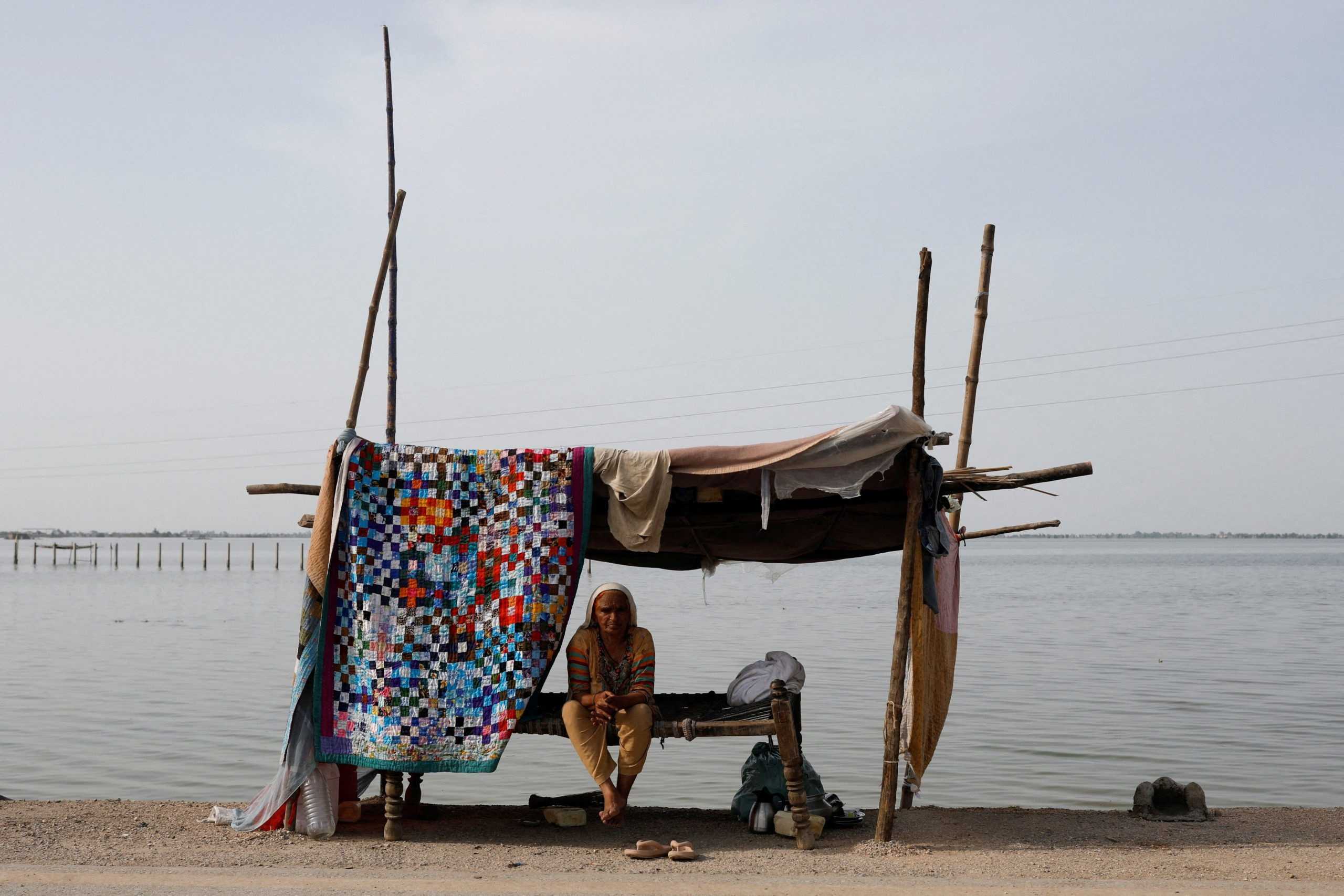 a flood victim takes refuge along a road in a makeshift tent following rains and floods during the monsoon season in mehar pakistan august 29 2022 reuters akhtar soomro