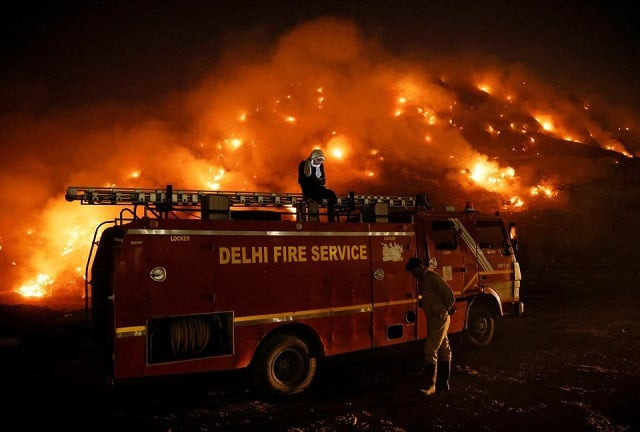 a firefighter uses his mobile phone as he sits on top of a fire truck as smoke billows from burning garbage at the bhalswa landfill site in new delhi india april 27 2022 photo reuters a firefighter uses his mobile phone as he sits on top of a fire truck as smoke billows from burning garbage at the bhalswa landfill site in new delhi india april 27 2022 photo reuters