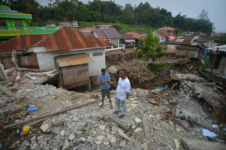 men stand near a damaged house in an area affected by flash floods in tanah datar west sumatra province indonesia may 14 2024 photo reuters