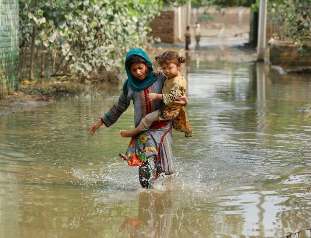 a girl carries her sibling as she walks through stranded flood water following rains and floods during the monsoon season in nowshera photo reuters file