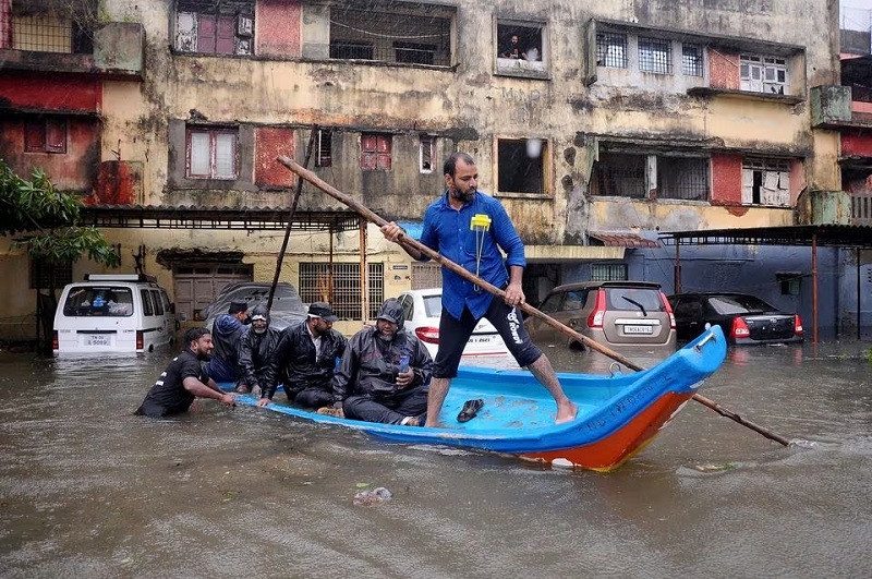 people move past partially submerged vehicles following heavy rains ahead of cyclone michaung in chennai india december 4 2023 photo reuters