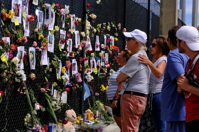 people mourn at the memorial site created by neighbors in front of the partially collapsed building where the rescue personnel continue their search for victims in surfside near miami beach florida us june 26 2021 photo reuters