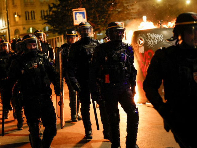 a group of police officers walk as people protest following the death of nahel a 17 year old teenager killed by a french police officer in nanterre during a traffic stop and against police violence in paris france june 30 2023 photo reuters a group of police officers walk as people protest following the death of nahel a 17 year old teenager killed by a french police officer in nanterre during a traffic stop and against police violence in paris france june 30 2023 photo reuters