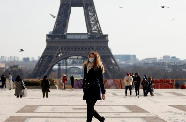a woman wearing protective face masks walks in front of the eiffel tower at the trocadero in paris amid the coronavirus disease covid 19 outbreak in france february 11 2021 photo reuters