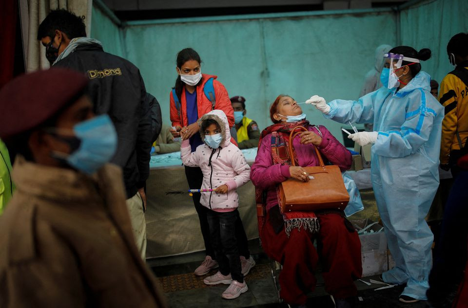 a healthcare worker collects a coronavirus disease covid 19 test swab sample from a woman amidst the spread of the disease at a railway station in new delhi india january 5 2022 reuters