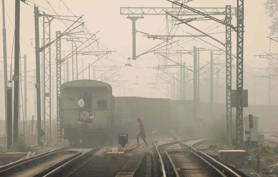 a woman crosses railway tracks as a goods train passes by on a smoggy day in new delhi india november 12 2021 photo reuters