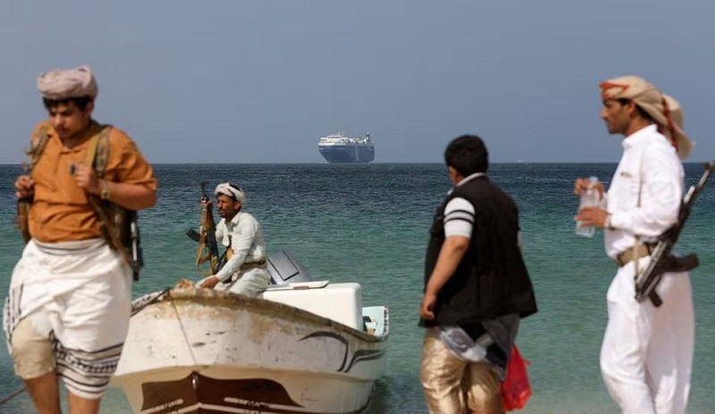 Gunmen stand on the beach as the merchant ship Galaxy Leader, seized by Yemen's Houthis last month, is anchored off the coast of al-Salif, Yemen, December 5, 2023. PHOTO: REUTERS