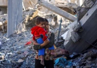 a palestinian boy carrying a baby stands at a site of israeli strikes in rafah in the southern gaza strip photo reuters