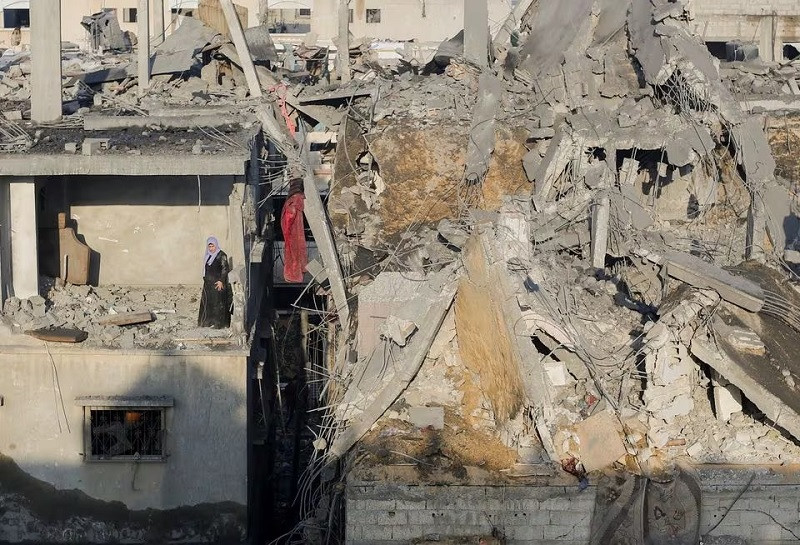 A Palestinian woman stands in a damaged building as she inspects the site of Israeli raids in Khan Younis in the southern Gaza Strip.  PHOTO: REUTERS