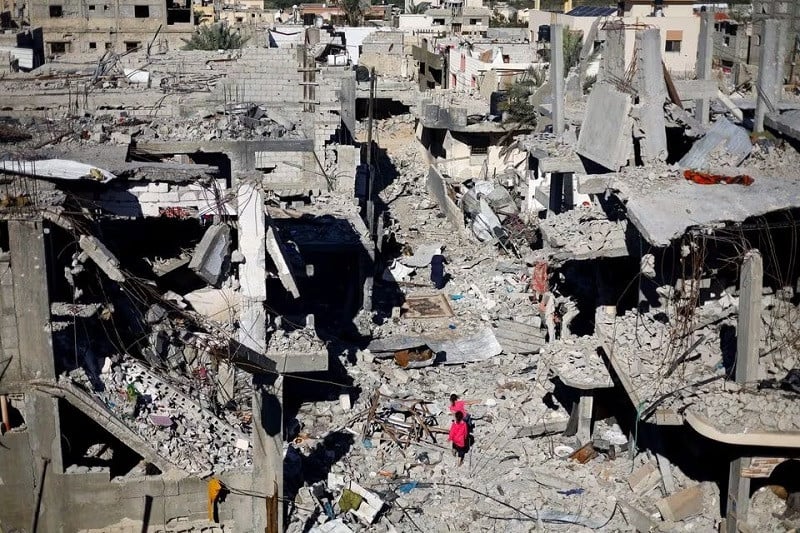 Palestinian children travel among a houses broken in Israeli strikes during Khan Younis interloper camp, in a southern Gaza Strip, Nov 29, 2023. PHOTO: REUTERS