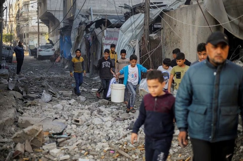 palestinian children carry items as they walk at the site of israeli strikes in khan younis in the southern gaza strip december 6 2023 photo reuters