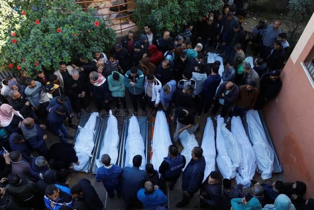 people stand next to bodies of palestinians killed in israeli strikes during a funeral at nasser hospital in khan younis in the southern gaza strip december 9 2023 photo reuters