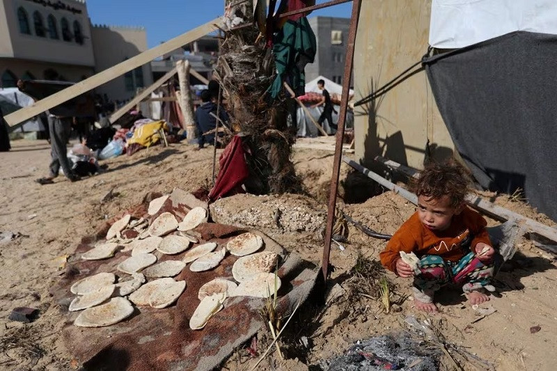 A child cooking outward a tent, as replaced Palestinians preserve in a stay in Rafah in a southern Gaza Strip, Dec 6, 2023. PHOTO: REUTERS