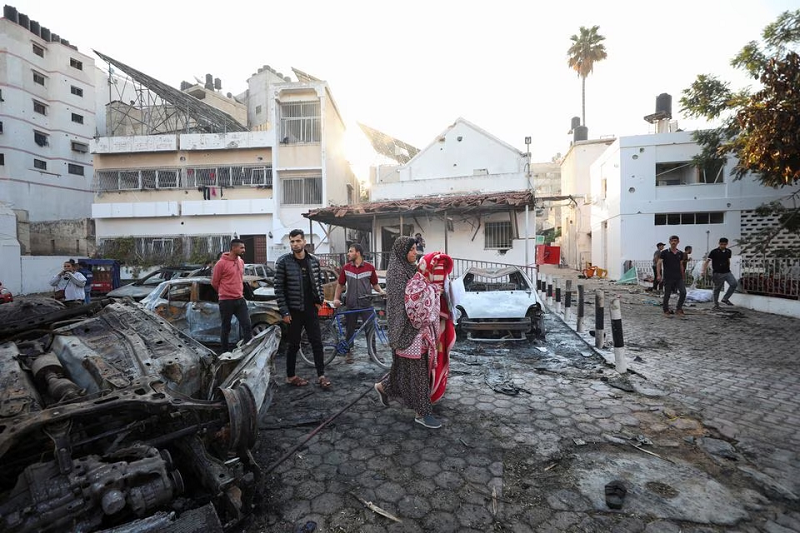People inspect the area of Al-Ahli hospital where hundreds of Palestinians were killed in a blast, in Gaza City, October 18. PHOTO: REUTERS/FILE