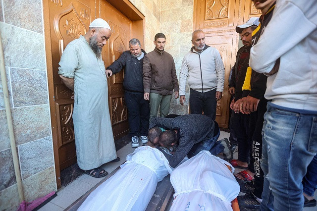 Men mourn over the body of a person killed in Israeli bombardment on Khan Yunis in the southern Gaza Strip, in front of the morgue of the Nasser hospital on December 15, 2023, as battles continue between Israel and the Palestinian resistance group Hamas. PHOTO: AFP