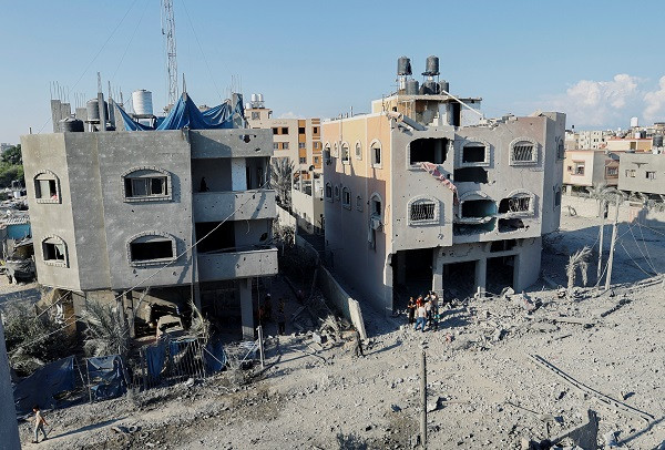 A view of damaged houses as Palestinians gather near it, at a site of Israeli strikes in Khan Younis in the southern Gaza Strip. PHOTO: Reuters