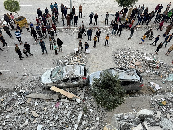 Palestinians gather near damaged vehicles in the aftermath of an Israeli strike on an apartment in a residential building, in Khan Younis in southern Gaza. PHOTO: AFP