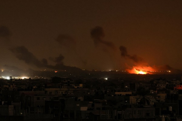 This design taken from Rafah, shows fume and glow rising above buildings during Israeli strikes on eastern Khan Yunis in a southern Gaza Strip. PHOTO: AFP