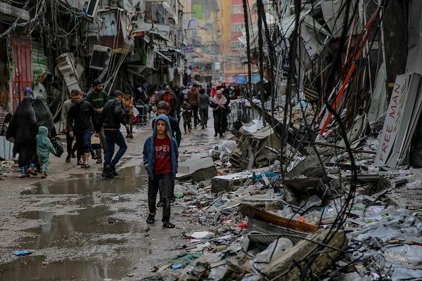 Palestinians walk among the debris of buildings hit by Israeli strikes, near the Al-Zawiya market in Gaza City.  PHOTO: AFP