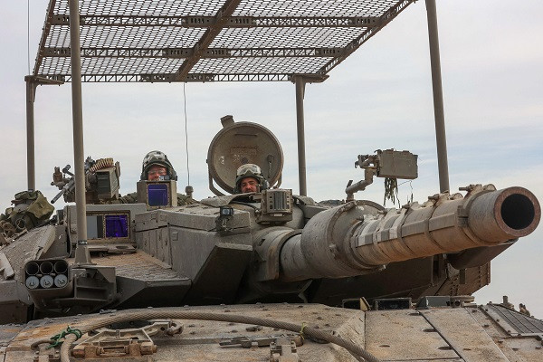 Israeli troops prepare weapons and military vehicles by the border fence before entering the Gaza Strip. PHOTO: AFP