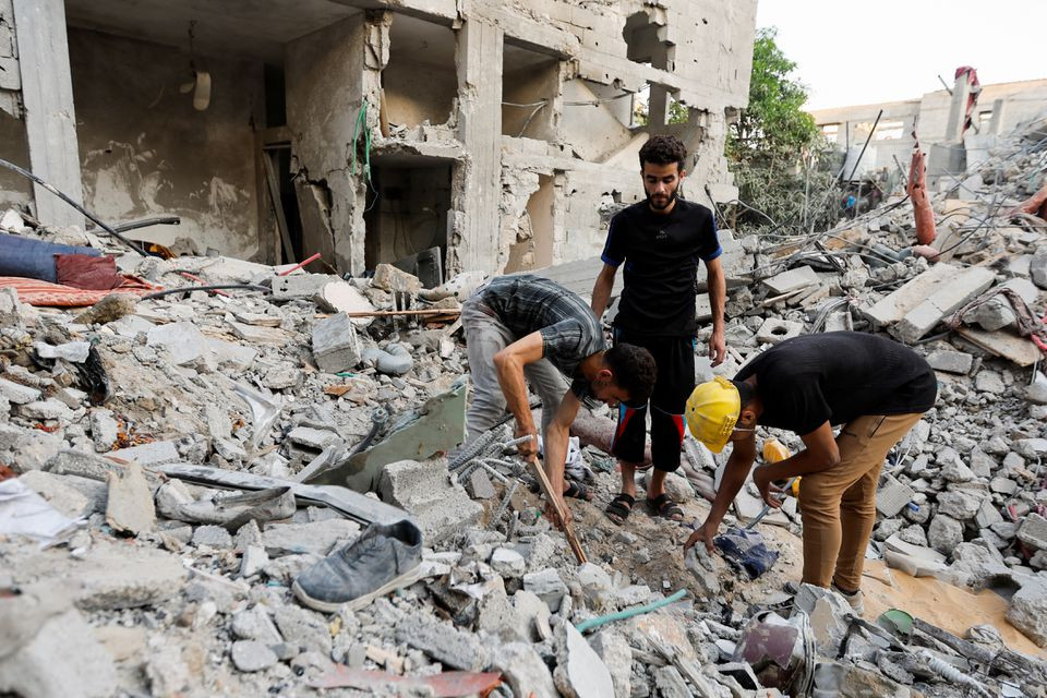 palestinians men look through debris as people gather at the scene where senior commander of islamic jihad group khaled mansour was killed in israeli strikes in rafah in the southern gaza strip august 7 2022 reuters