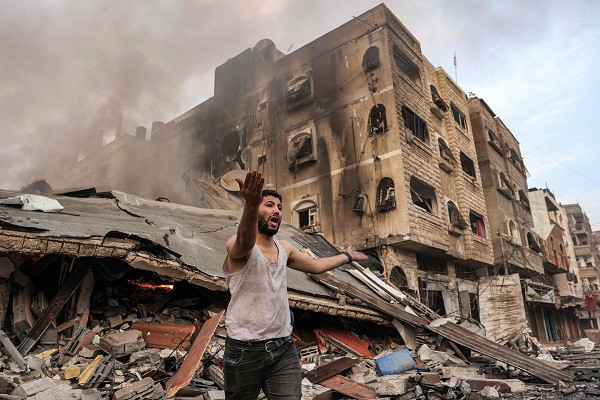 a man reacts outside a burning collapsed building following israeli bombardment in gaza city photo afp