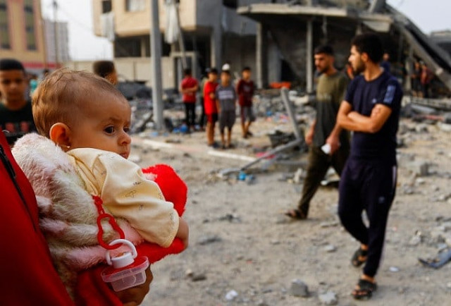 a person holds a child as palestinians gather at the site of israeli strikes on a house in khan younis in the southern gaza strip photo reuters a person holds a child as palestinians gather at the site of israeli strikes on a house in khan younis in the southern gaza strip photo reuters