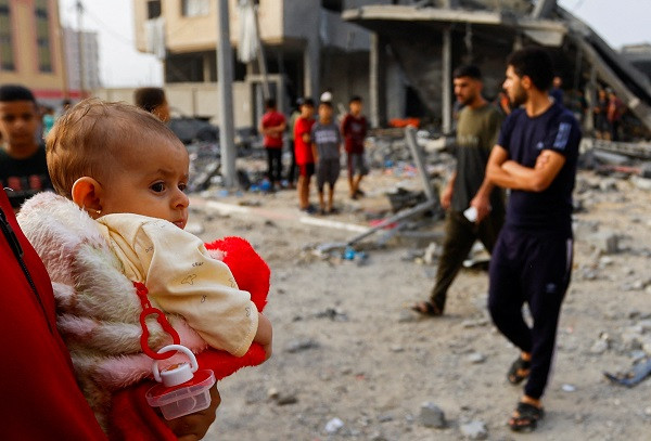 a person holds a child as palestinians gather at the site of israeli strikes on a house in khan younis in the southern gaza strip photo reuters