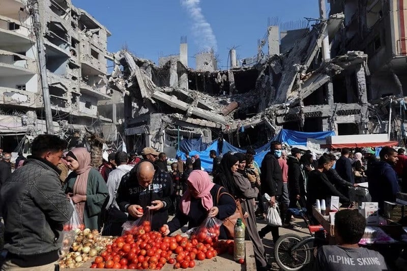 Palestinians shops in an open-air market near the ruins of houses and buildings destroyed in Israeli strikes in Nuseirat refugee camp in the central Gaza Strip November 30. PHOTO: REUTERS