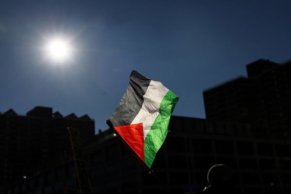 A Pro-Palestinian demonstrator waves the Palestinian flag while blocking a Brooklyn Bridge roadway during a 'Shut it Down for Palestine' protest in New York City. PHOTO: Reuters