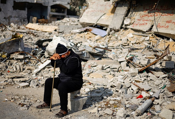 ziad mansour a neighbour of the abu aweidah family sits next to writing painted on a wall amid the rubble of the family s house which was destroyed in a deadly israeli strike photo reuters