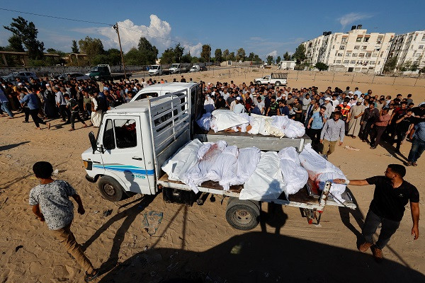 Mourners walk near to the bodies of Palestinians who were killed in Israeli strikes. PHOTO: Reuters
