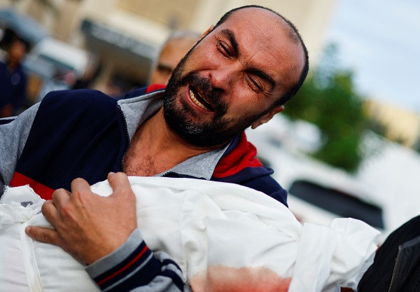 a palestinian man reacts as he carries the body of his niece hanan kaloob who was killed in an israeli strike at nasser hospital in khan younis photo afp