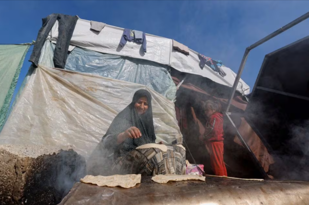 a child stands next to a cooking woman as displaced palestinians who fled their houses due to israeli strikes shelter in a tent camp near the border with egypt photo reuters