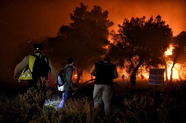 Firefighters and volunteers try to extinguish a wildfire burning in the village of Schinos, near Corinth, Greece, May 19, 2021. PHOTO: REUTERS