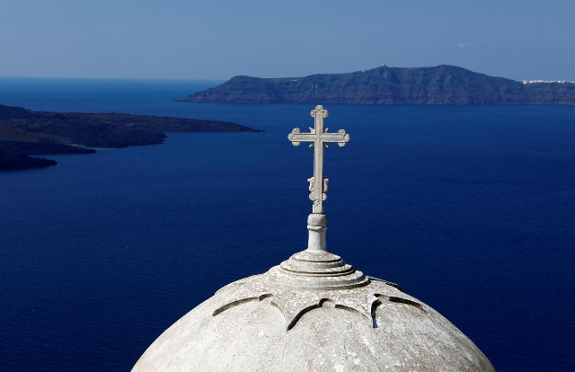 volcanic islets are seen behind a greek orthodox church built on the edge of the caldera at the volcanic island of santorini photo reuters file