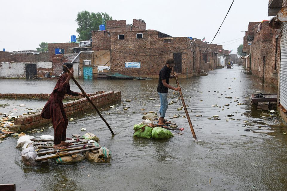 Men paddle on makeshift rafts as they cross a flooded street, amidst rainfall during the monsoon season in Hyderabad, Pakistan August 24, 2022. REUTERS