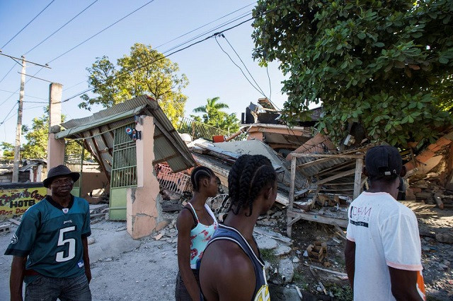 people walk past a house destroyed following a 7 2 magnitude earthquake in les cayes haiti august 14 2021 photo reuters